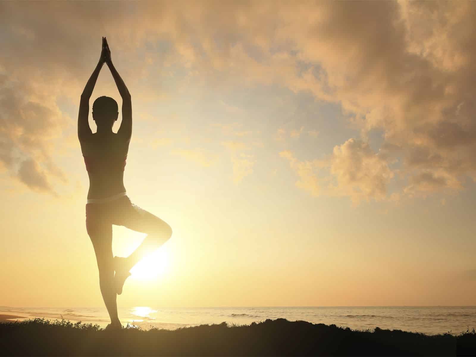 Práctica de yoga en la playa al atardecer para mejorar la salud y reducir peso con cirugía bariátric.