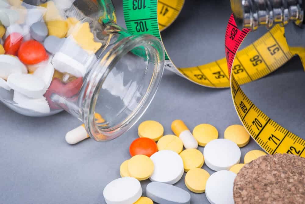 Pastillas y medicamentos con cinta métrica, salud y control en medicina estética y cirugías.